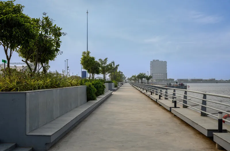 Waterfront promenade with concrete planters and metal railings under clear daytime sky
