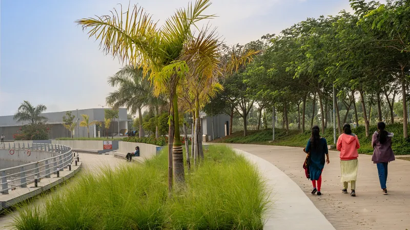 Paved pedestrian path bordered by palms and ornamental grasses with three visitors walking at dusk