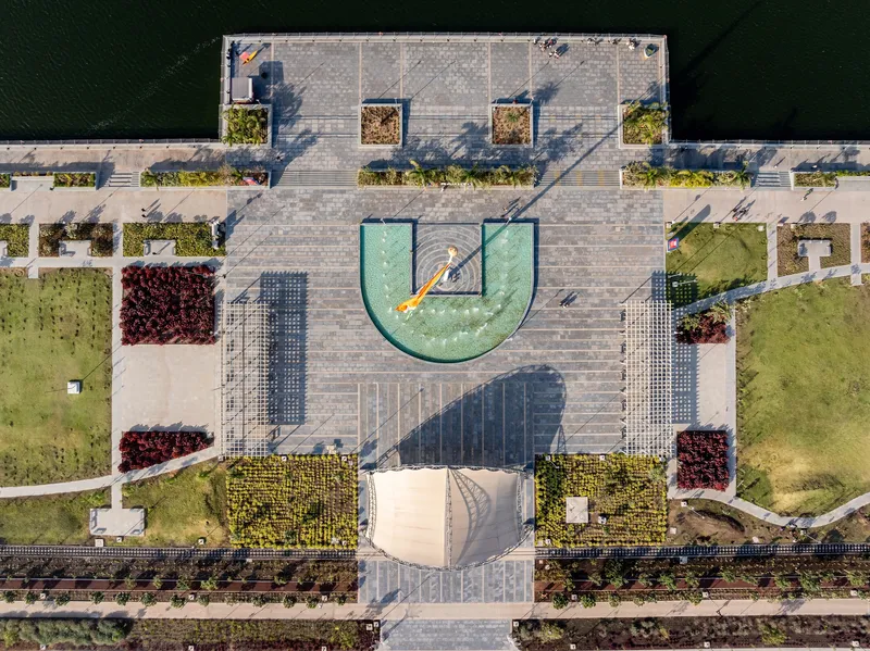 Aerial view of the paved plaza with U-shaped fountain and planted beds casting morning shadows