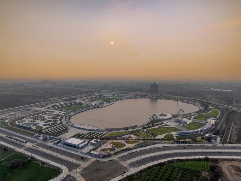 Aerial perspective of the circular lake surrounded by curved parkland and roadways at sunset