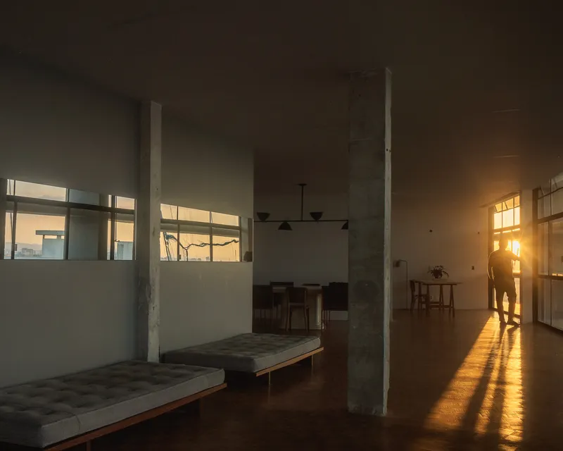 Open living space with concrete columns and clerestory windows casting warm afternoon sunlight across parquet floors