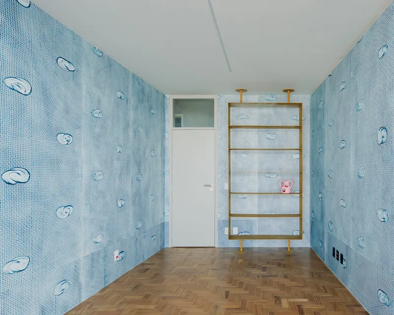Light blue mosaic tile room with fish motif and brass ladder shelving on herringbone flooring