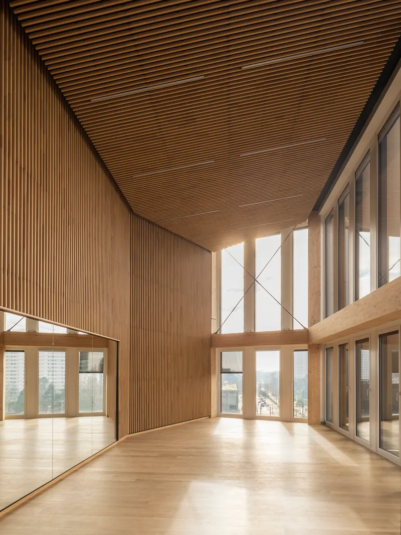 Double-height space with slatted timber ceiling and floor-to-ceiling windows overlooking the cityscape