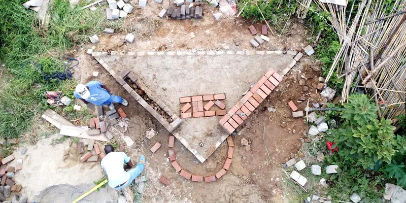 Overhead view of foundation layout with red brick coursing and workers during early construction phase