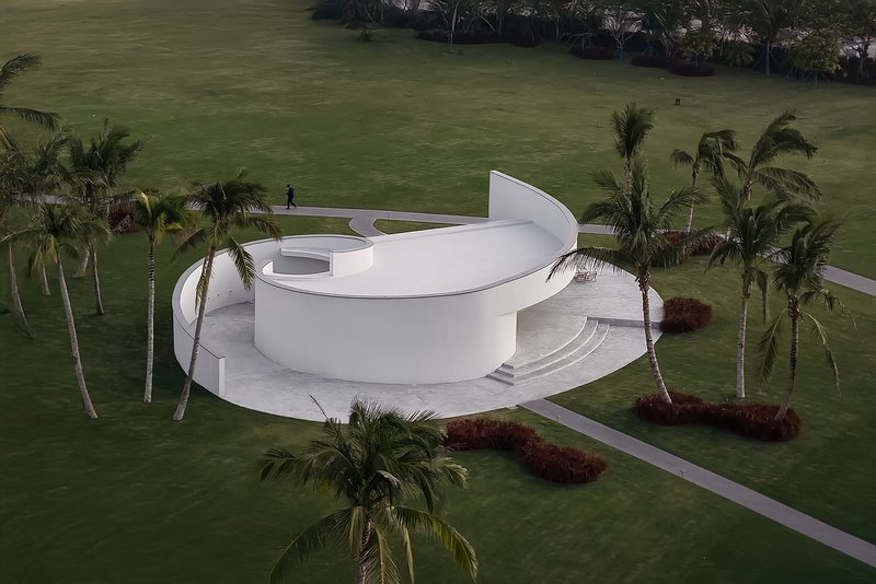 Aerial view of the spiraling white chapel surrounded by palm trees on a landscaped lawn
