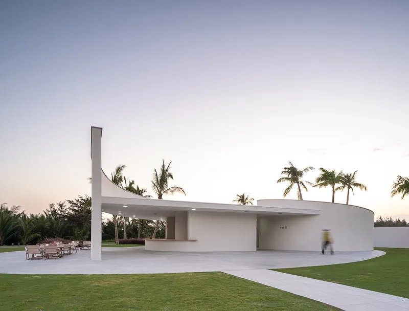 Entrance facade with vertical chimney element and covered terrace seating at dusk