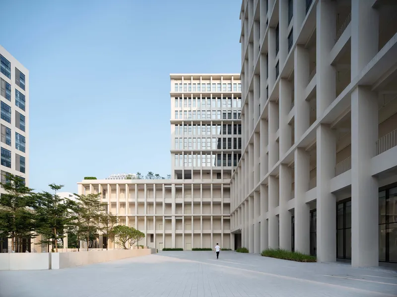 Plaza framed by precast concrete facades with deep vertical fins and a lone pedestrian