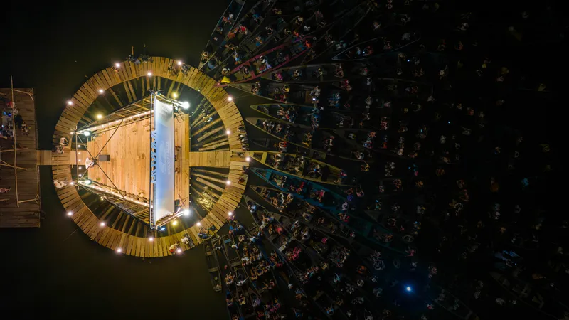 Overhead view of the circular deck with central stage surrounded by audience in boats at night