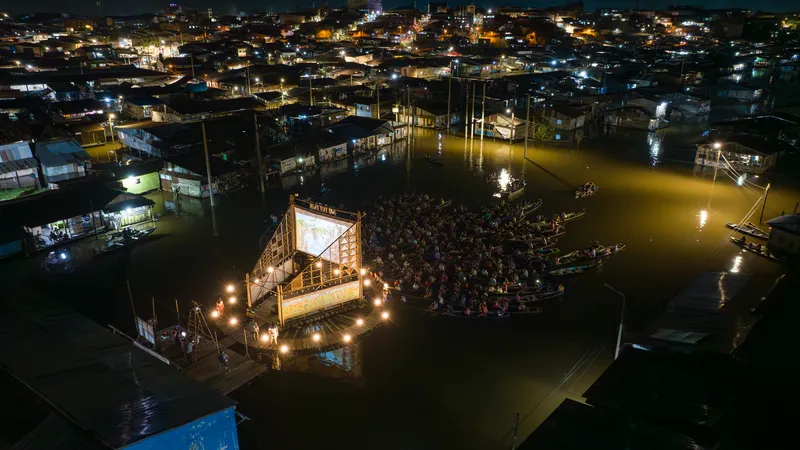 Night aerial view of the illuminated floating pavilion with gathered boats in floodwater