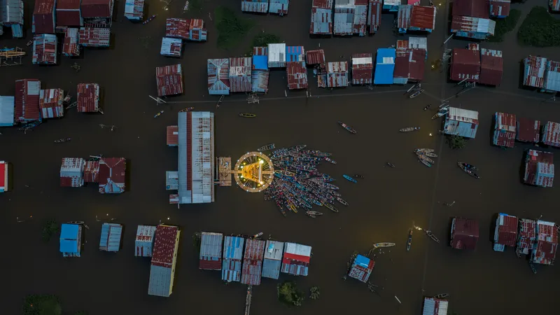 Drone view of the illuminated floating screen surrounded by boats and corrugated metal houses on water