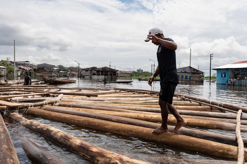 Person walking across a floating platform made of lashed timber logs during an overcast day