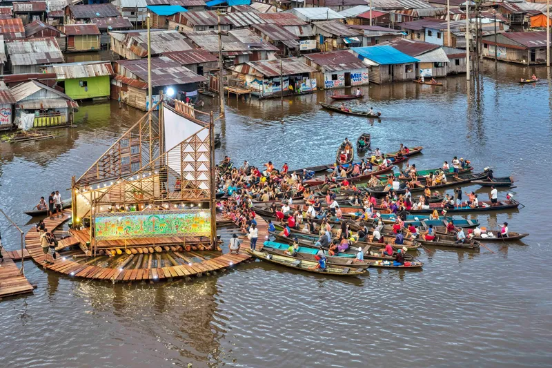 Floating timber platform stage surrounded by dozens of canoes gathering in the water