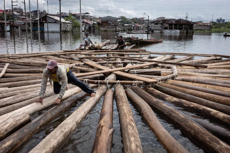 Workers assembling lashed timber log raft foundation in a flooded residential area
