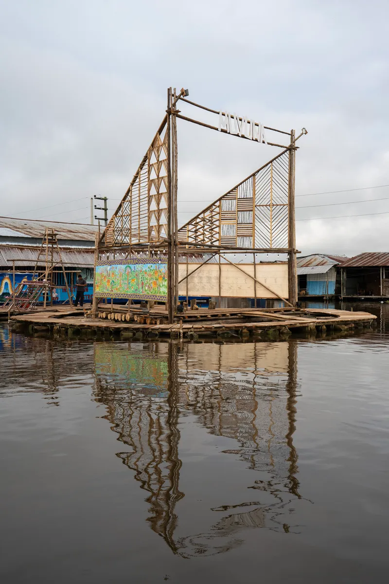 Floating bamboo and timber stage platform with geometric panels reflected in still water