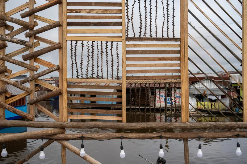 Timber frame panels with hanging shell decorations and string lights reflected in standing water