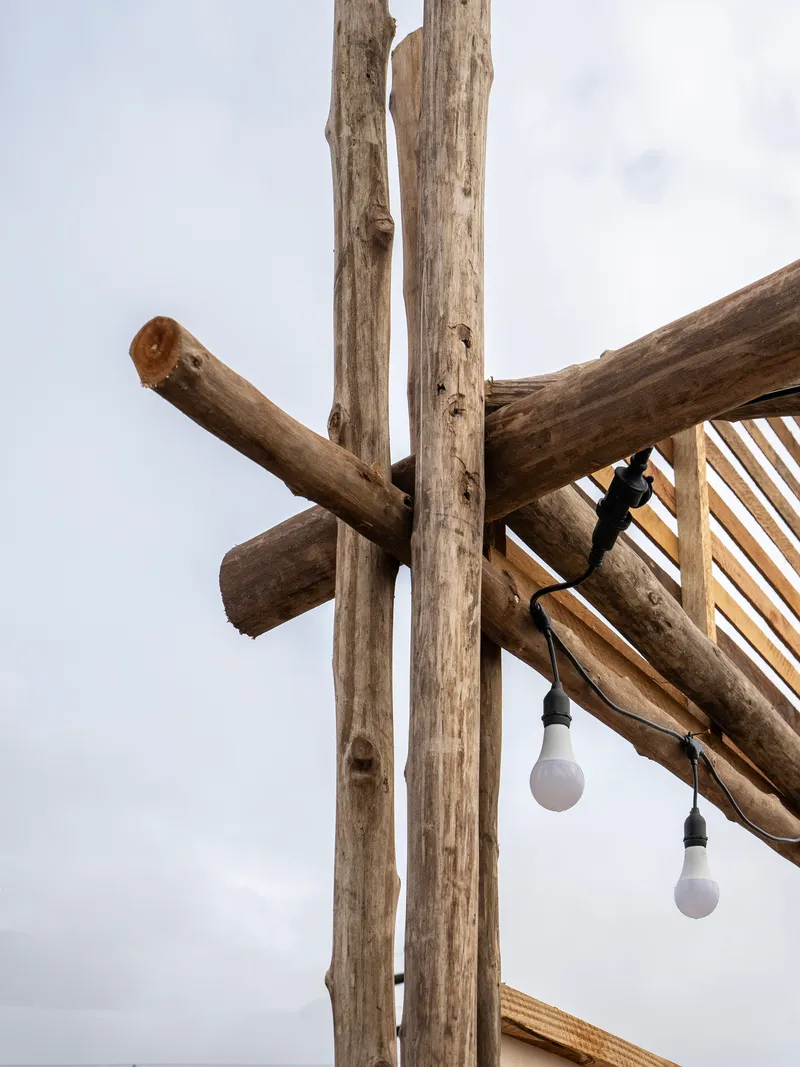 Close-up of notched timber column joint with two hanging bulbs against cloudy sky