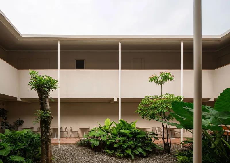Open-air courtyard with planted beds, white columns and recessed wall niches under overcast sky