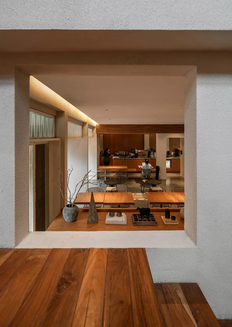 Deep window opening framing the dining area with timber flooring and overhead concealed lighting