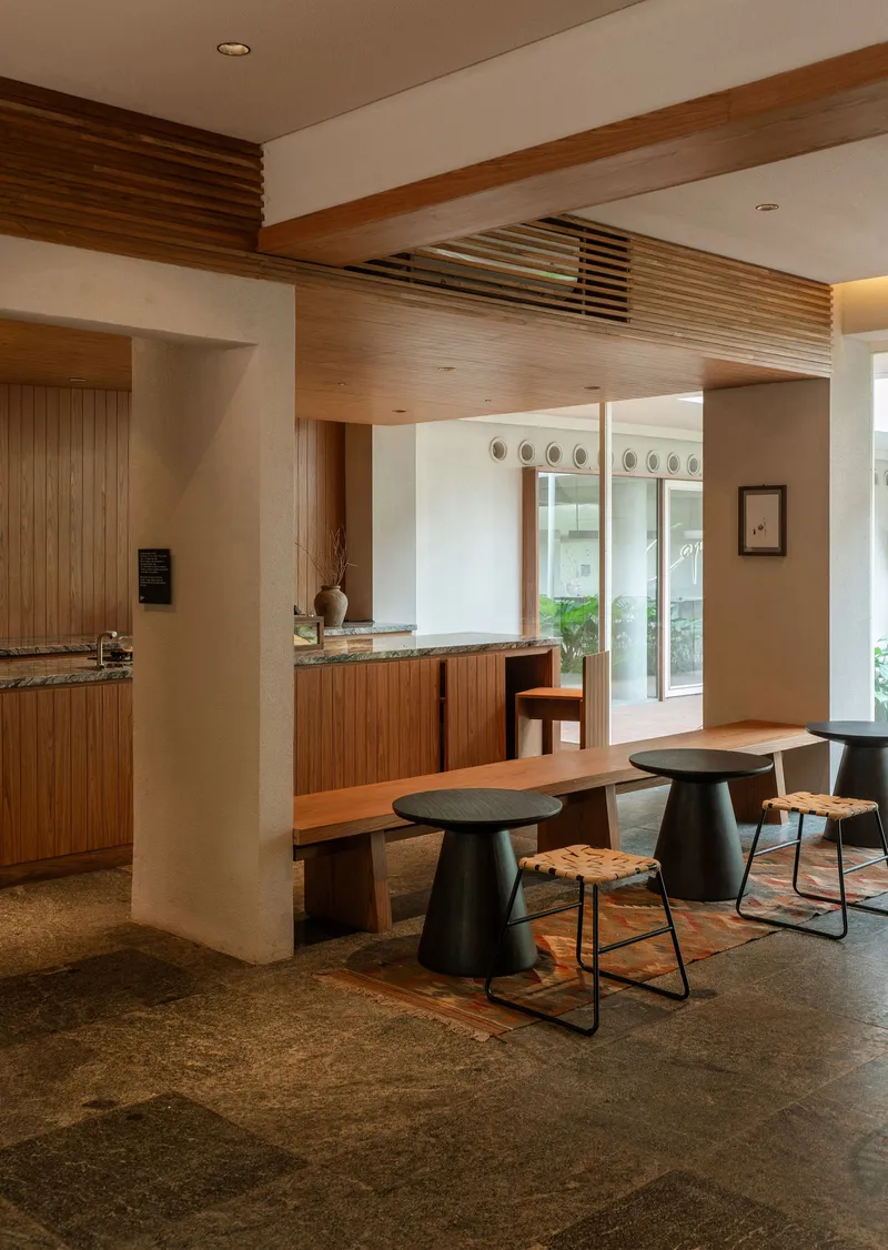 Open kitchen and dining space with ribbed timber cabinetry and dark terrazzo flooring
