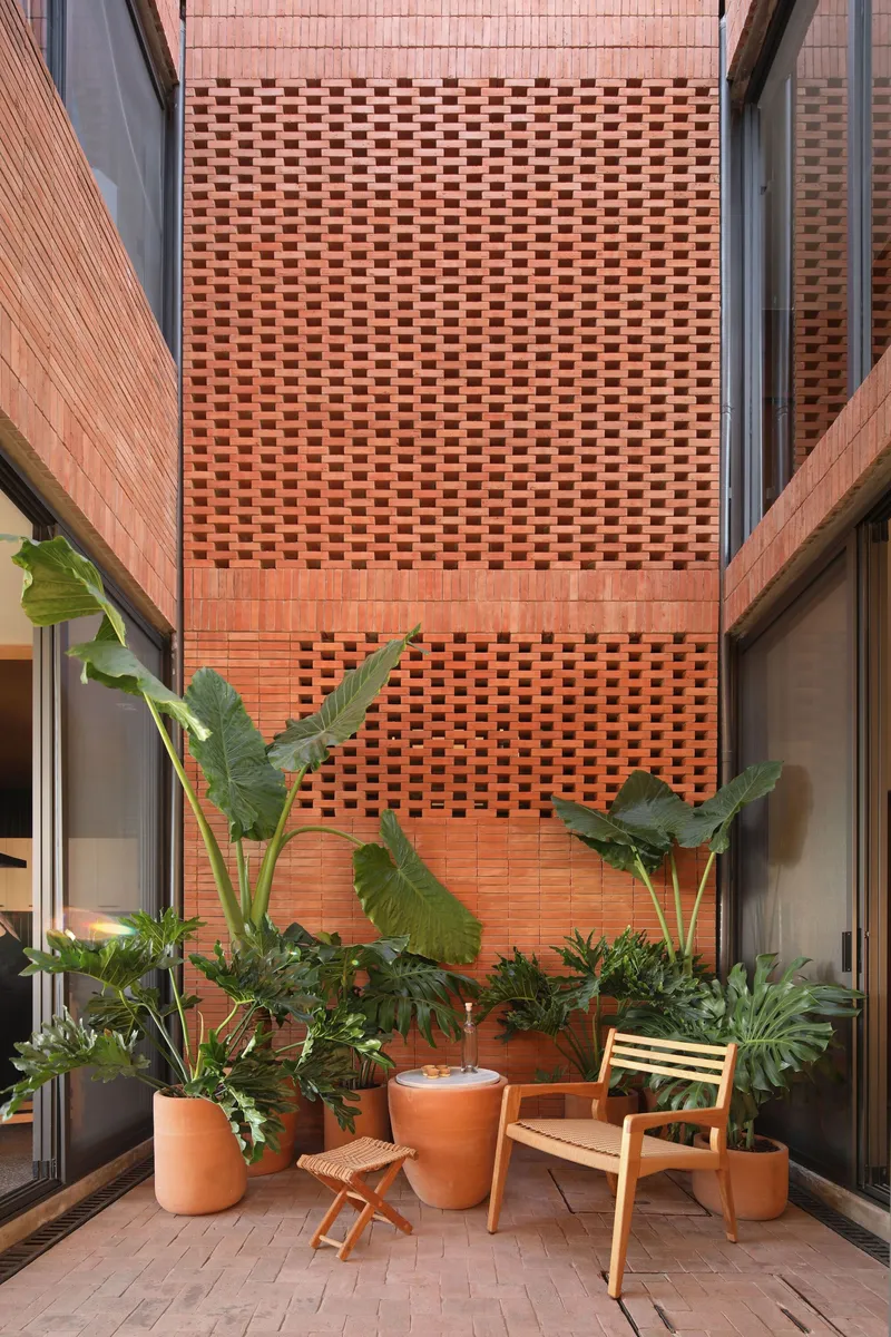 Courtyard terrace with perforated brick screen wall and potted tropical plants