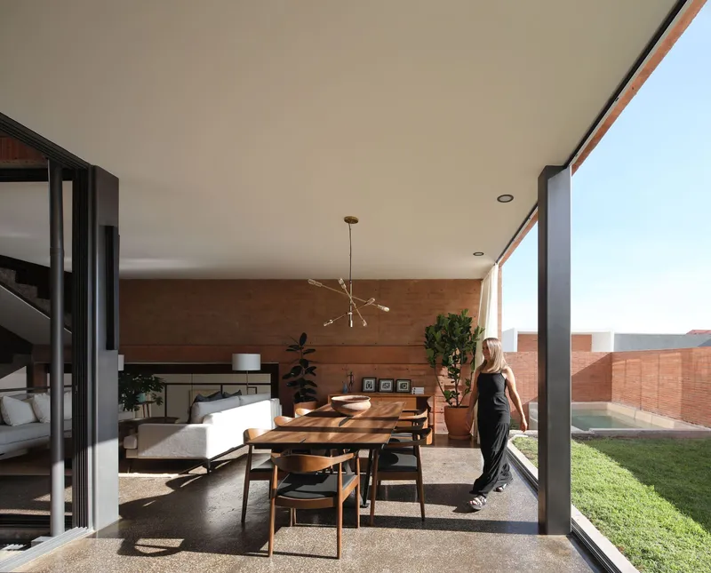 Living and dining space opening to lawn through full-height glazing
