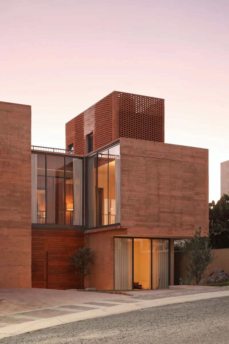 Street-facing elevation showing perforated brick screen above glass-walled living space with timber cladding at ground level