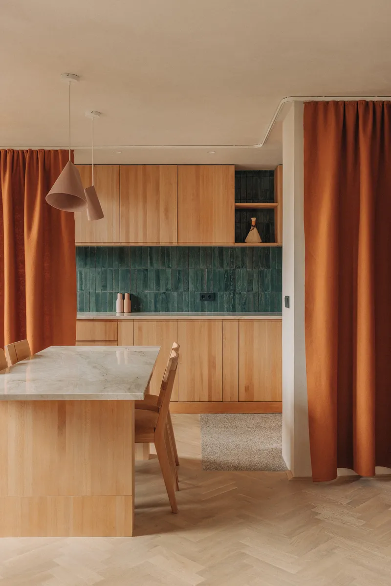 Dining area with pendant light and green tile backsplash framed by orange curtain panels