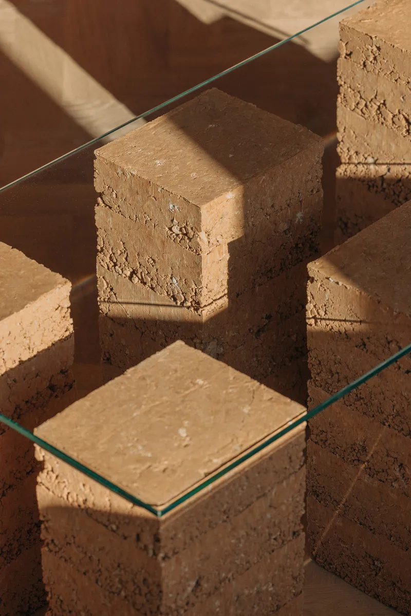 Close-up of stacked cork blocks topped with clear glass under direct sunlight