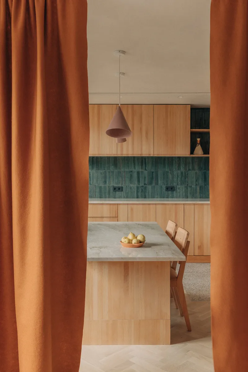 Kitchen glimpsed through terracotta curtains showing green tile backsplash and pendant light above dining table
