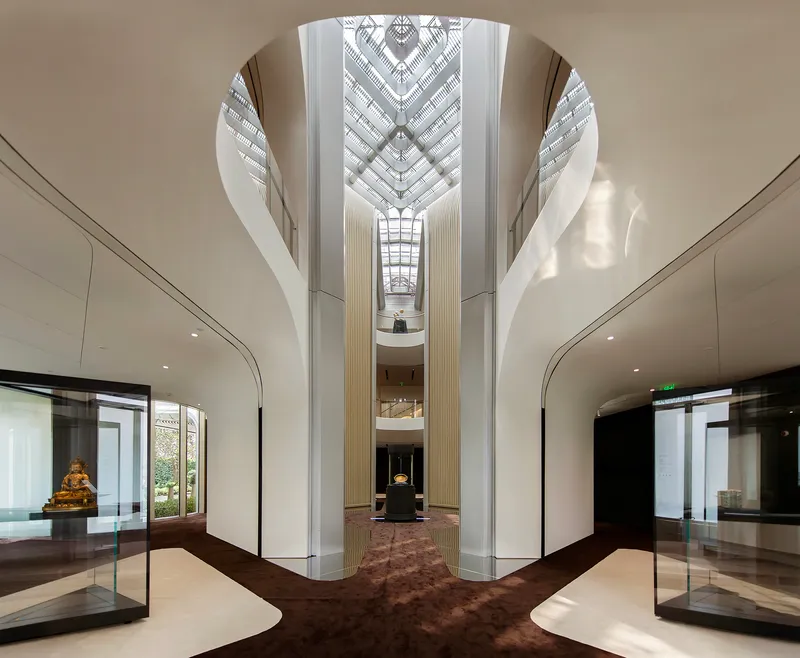 Multi-story atrium with fluted white columns and diamond-patterned skylight above a central display case