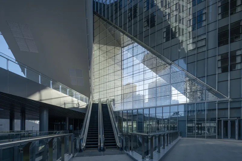Covered atrium courtyard with twin escalators rising beneath the angled glass overhang