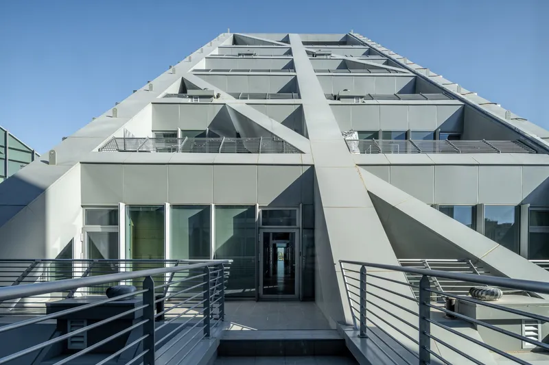 Rooftop terrace with white diagonal bracing and horizontal metal railings under clear sky