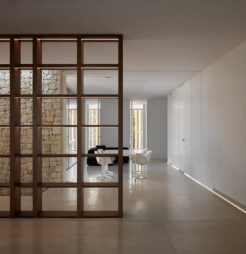 Dark timber framed glass partition dividing the corridor from the dining room with concealed floor lighting