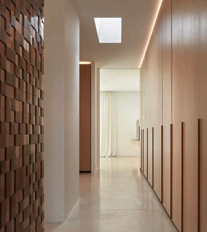 Corridor with terracotta tile feature wall, wood-clad storage and skylight overhead
