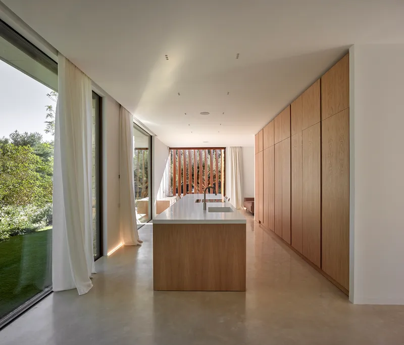 Kitchen with oak island and full-height cabinetry opening to a vertical timber screen beyond