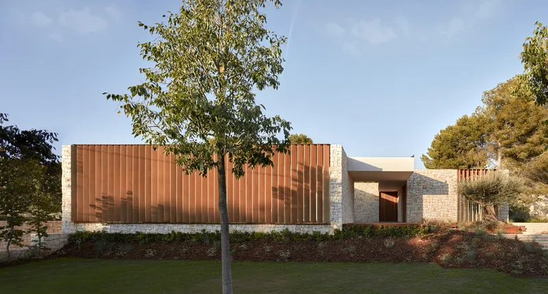 Street view showing vertical timber screen and stone plinth base with trees emerging from planted beds