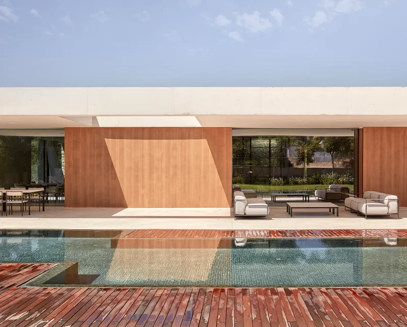 Poolside terrace with angled timber panels beneath a white concrete overhang and timber deck surround