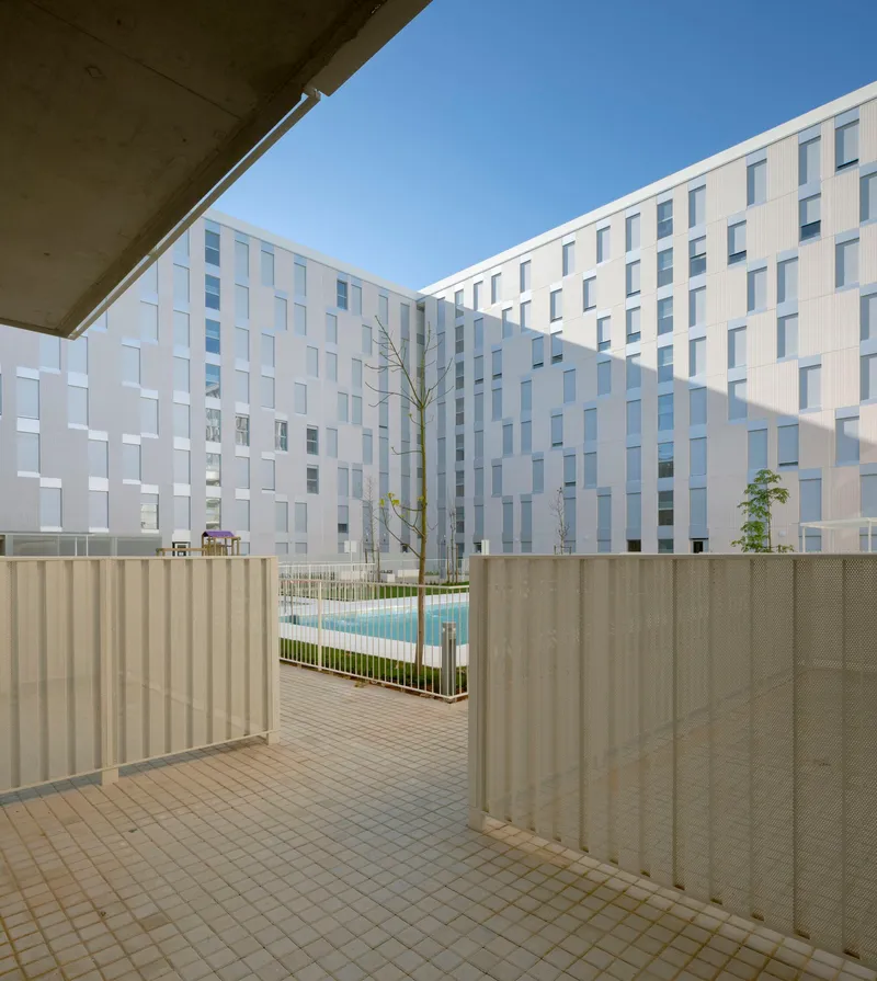 Courtyard terrace with perforated metal screening, bare trees and pool visible beyond timber decking