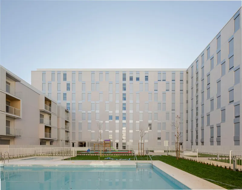 Courtyard view showing chequered facade panels, a reflecting pool, and newly planted trees
