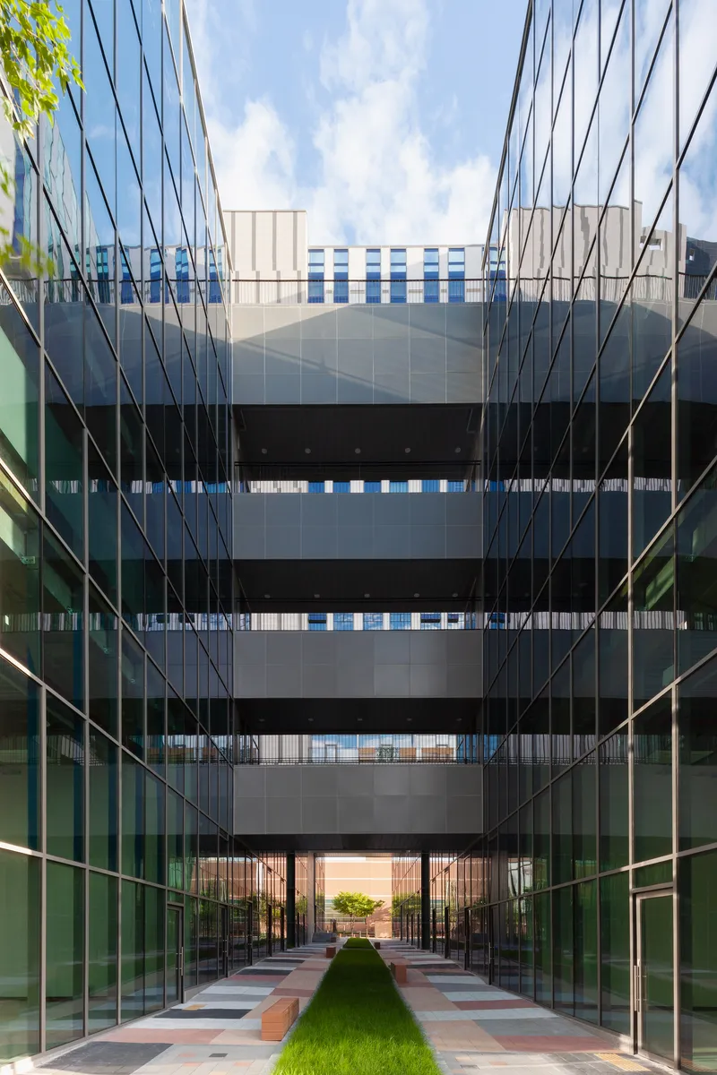 Central courtyard with glass walls on both sides and a grass strip leading to the entry