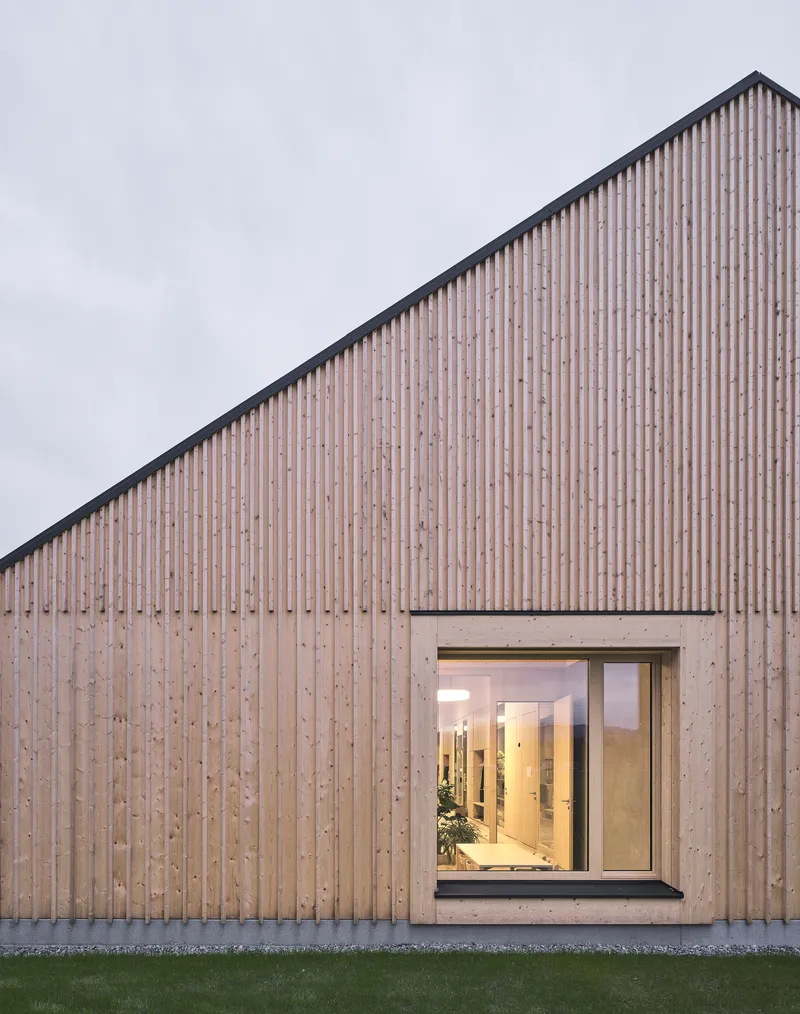 Close view of the vertical wood slat cladding and concrete-framed glazed opening