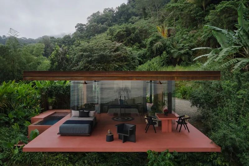 Elevated red terrace with glass-walled pavilion under a timber soffit surrounded by dense jungle vegetation
