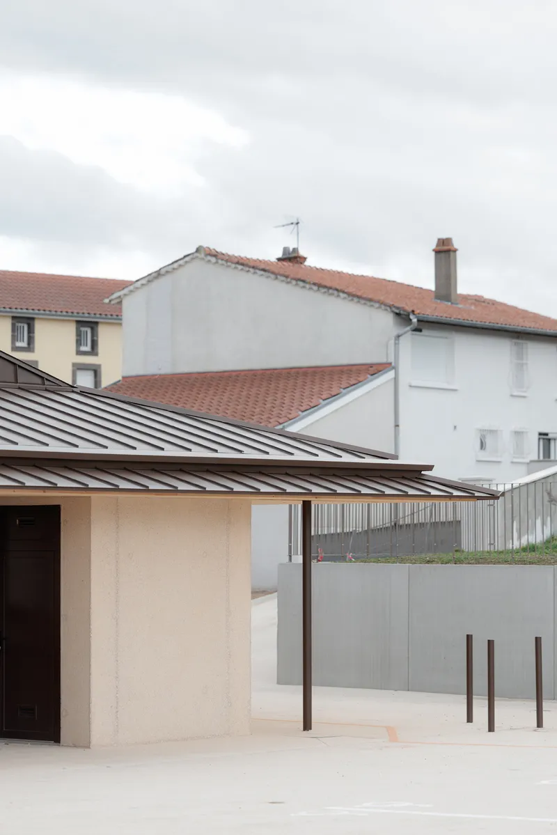 Canopy with dark standing seam metal roof supported by slender columns beside concrete bollards