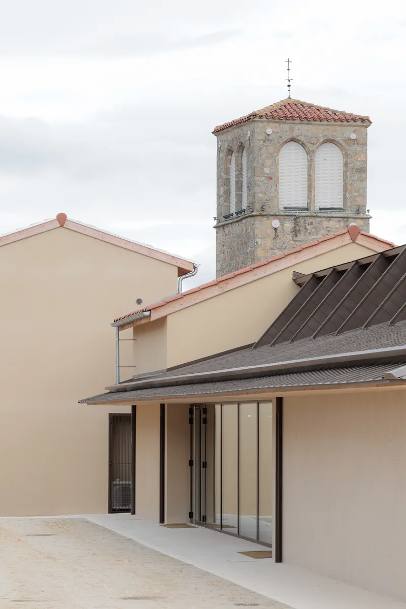 Canopy with angled metal roof below a stone bell tower with arched openings