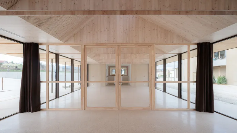 Interior view of a timber-clad space with glazed doors opening to a courtyard