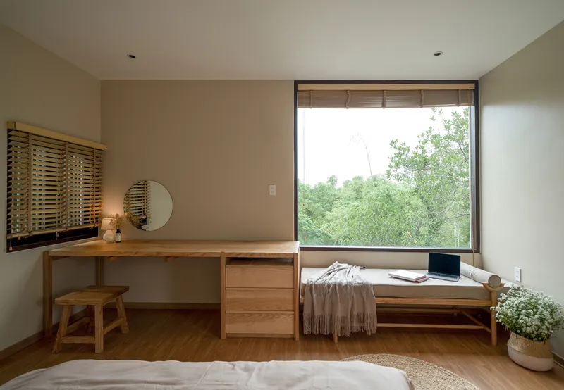 Bedroom with built-in timber desk and window seat overlooking green foliage