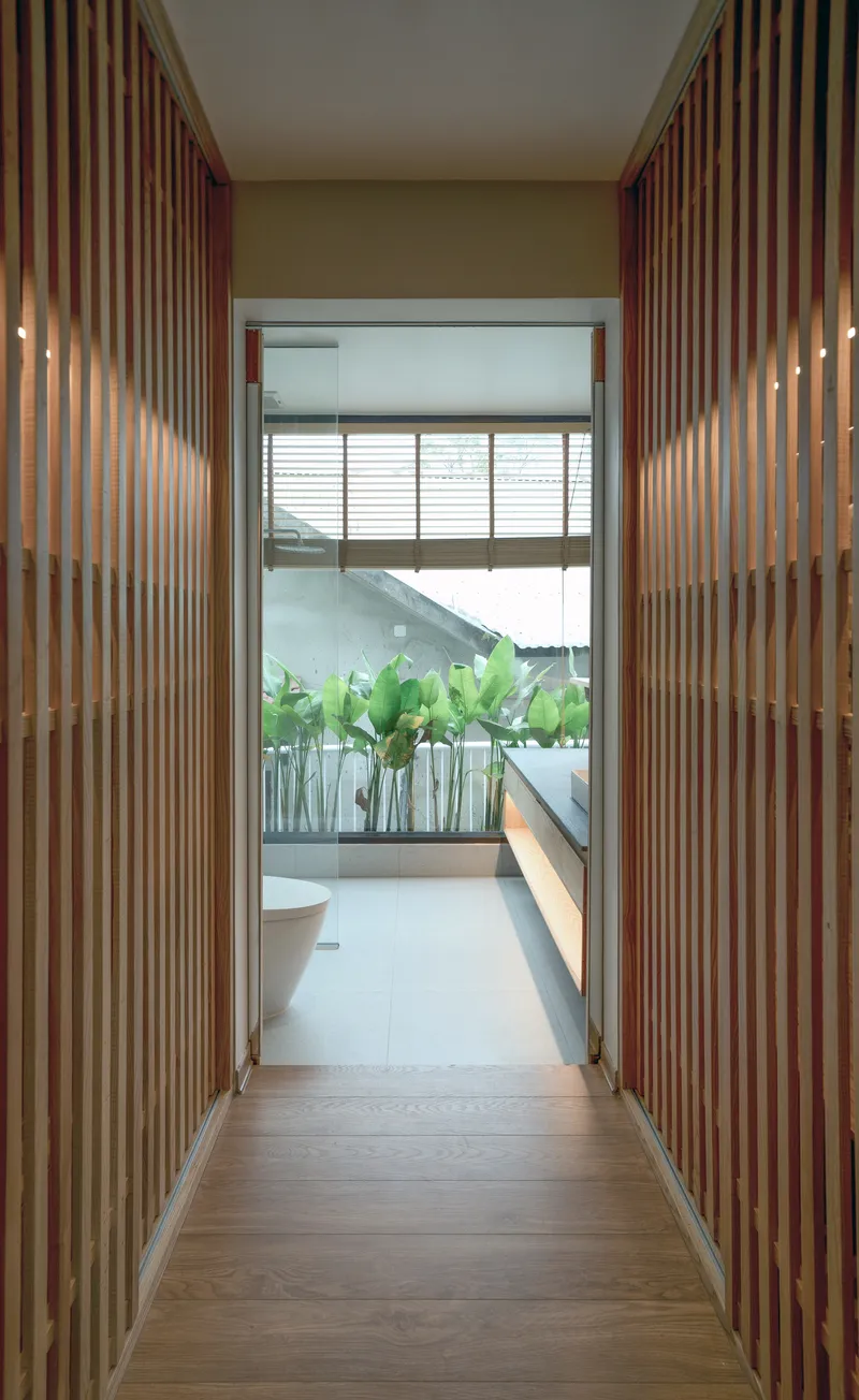 Corridor with vertical timber slat walls opening to a planted balcony