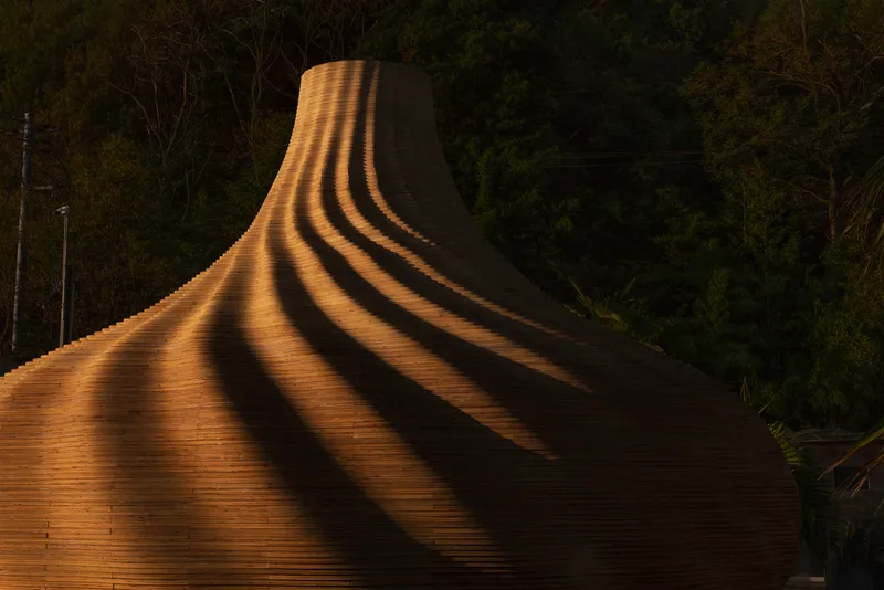 Bulbous timber shell with shadow striations cast across its ridged surface at night