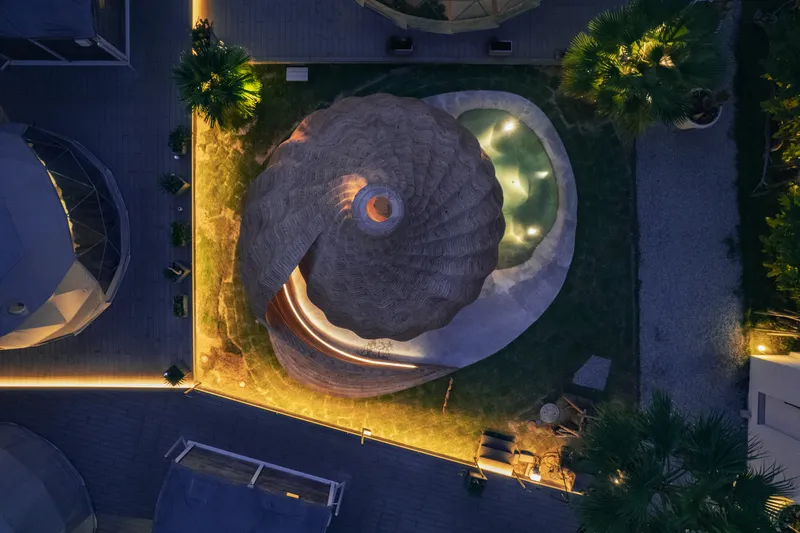 Aerial view of the timber pavilion with curved bench and reflecting pool at night