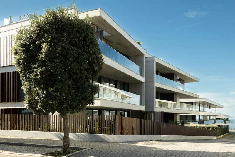 Corner view showing stacked horizontal slabs with glass railings and timber screening beneath a clear sky